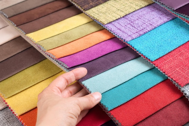 La main de femme choisit des échantillons de tissu coloré