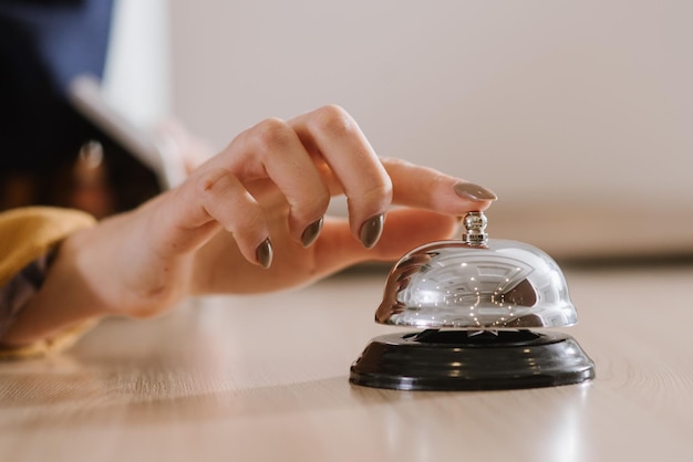Photo une main de femme sur la cloche de l'hôtel à la réception