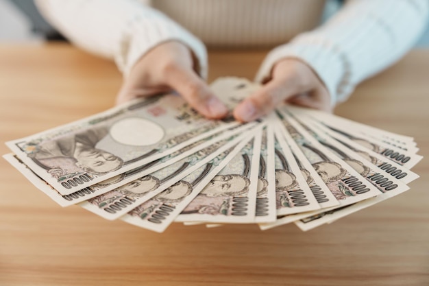 Main de femme comptant le billet de banque en yen japonais sur fond de table Mille yens d'argent Japon trésorerie Récession fiscale Économie Inflation Investissement finance épargne salaire et concepts de paiement