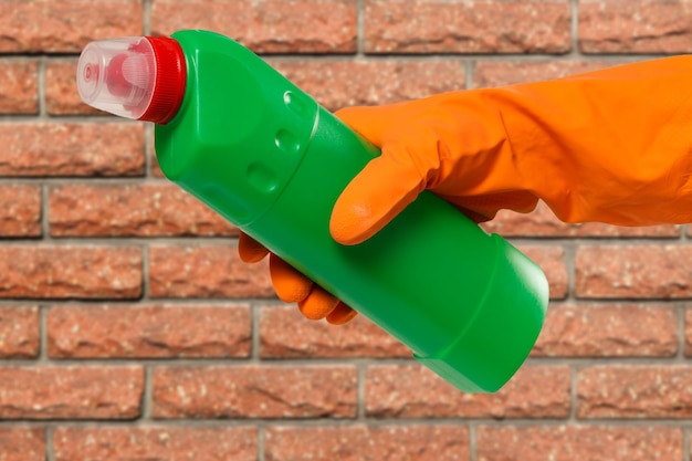 Main de femme dans un gant de protection avec une bouteille de liquide de lavage