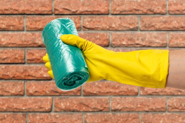 Main de femme dans un gant de protection avec des sacs poubelles