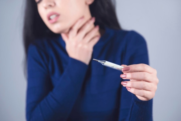 Main de femme dans la gorge et le thermomètre