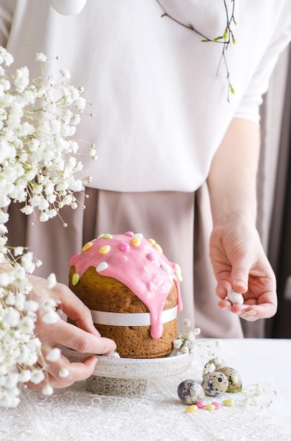 La main d'une femme décore un gâteau de Pâques avec une confiserie saupoudrant le concept des vacances de Pâques