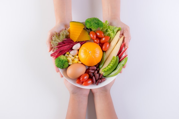 Photo main de femme donnant l'assiette de légumes frais