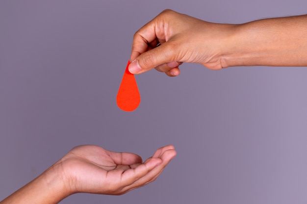 Main de femme donne un coeur rouge à une main de garçon pour le concept de don de sang, Journée mondiale du donneur de sang