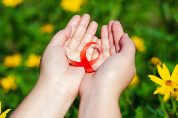 La main de la femme donne le ruban rouge sur le sol de la fleur.