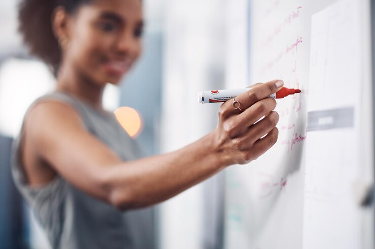 Photo la main de la femme et l'écriture avec un tableau blanc pour le coaching de présentation ou le brainstorming au bureau closeup d'une personne féminine créative prenant des notes à bord pour la planification d'un enseignement ou d'un atelier dans une start-up