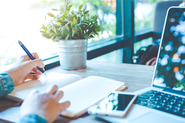 Main de femme écrivant sur le bloc-notes avec un stylo dans le bureau