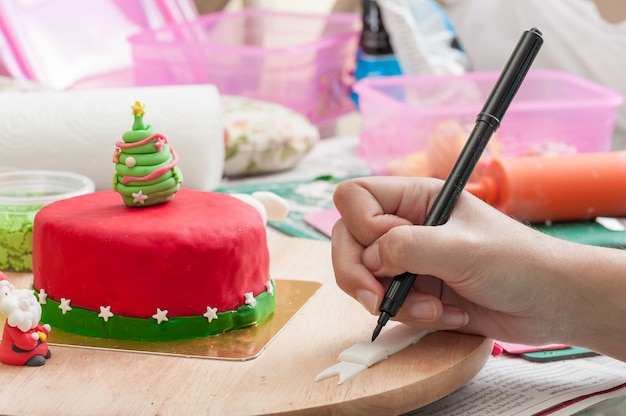 main de femme écrivant sur fondant avec stylo de qualité alimentaire