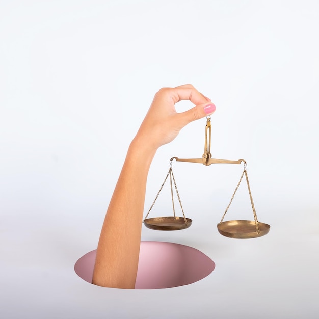 Photo main d'une femme à l'extérieur d'un trou tenant un équilibre sur fond rose et bleu