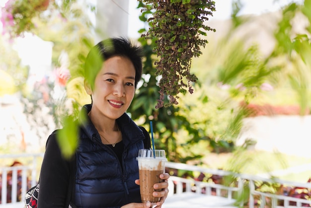 Main de femme heureuse tenant un café au lait glacé dans un café en plein air