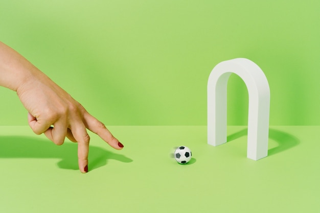 Photo main d'une femme inconnue jouant avec un ballon de football sur un but sur fond vert. concept de football et de sport.