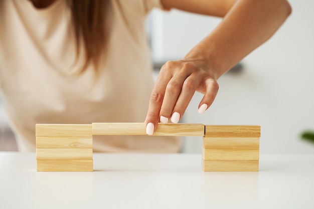 Main de femme d'ingénieur jouant un bloc de bois