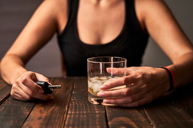 Main De Femme Ivre Tenant Un Verre D'alcool Et Une Clé De Voiture. Concept D'alcoolisme Et D'accidents De La Circulation Causés Par L'alcool.