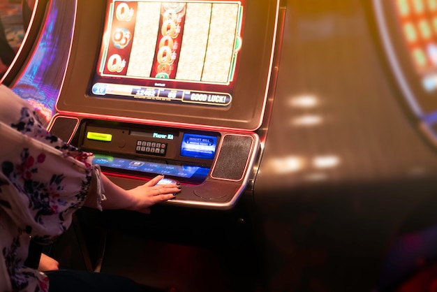 Main de femme jouant à la machine à sous au casino.