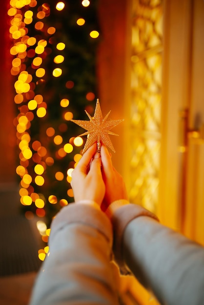 Main de femme avec des lumières de Noël sur l'arbre. Foire de Noël festive, concept de vacances d'hiver.