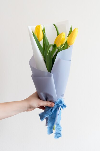 Main de femme avec manucure tenant des fleurs de printemps.