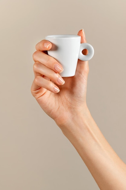 Photo la main d'une femme méconnaissable avec une tasse de café blanche.