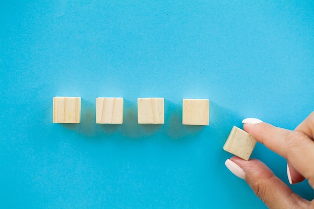 Main de femme mettant et empilant des cubes en bois vierges sur le bureau avec espace de copie pour le mot d'entrée