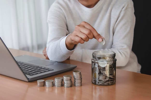 main de femme mettant une pièce d'argent dans une tirelire pour économiser de l'argent et du concept financier