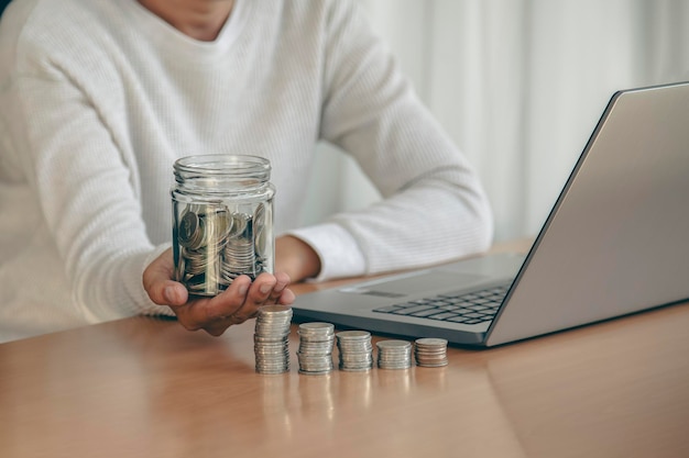 main de femme mettant une pièce d'argent dans une tirelire pour économiser de l'argent et du concept financier