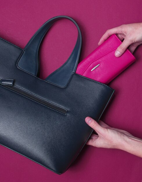 Main de femme mise dans le sac à main en cuir portefeuille rouge