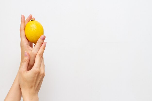 Main de femme avec la moitié du citron frais, espace libre pour le texte