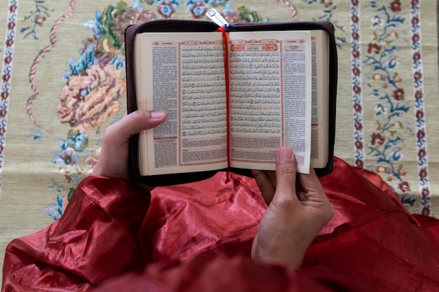 La main d'une femme musulmane tenant le Coran avec sa traduction en indonésien