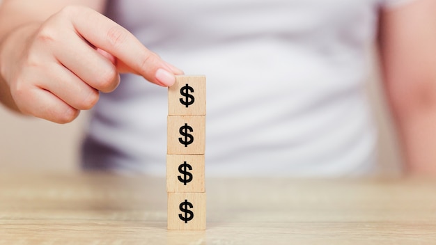 Photo main de femme organisant un bloc de bois avec icône argent dollar