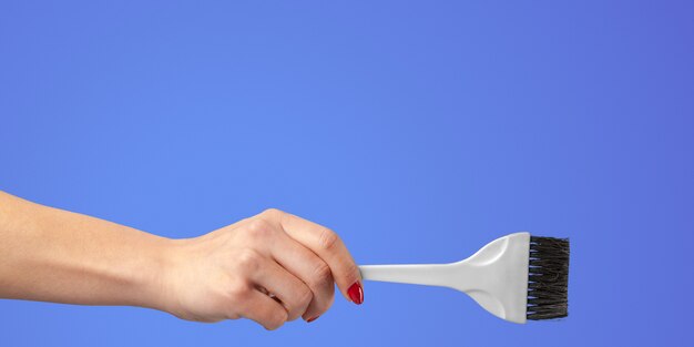 Photo main de femme avec des outils et des accessoires de coiffeur isolés sur fond de couleur