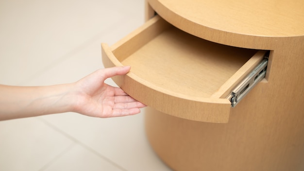 Main de femme ouvrant un tiroir dans la table en bois.