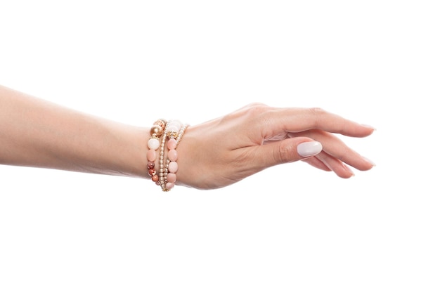 Main de femme parfaite portant un bracelet doré avec des perles d'opale rose et des perles d'or isolées sur fond blanc