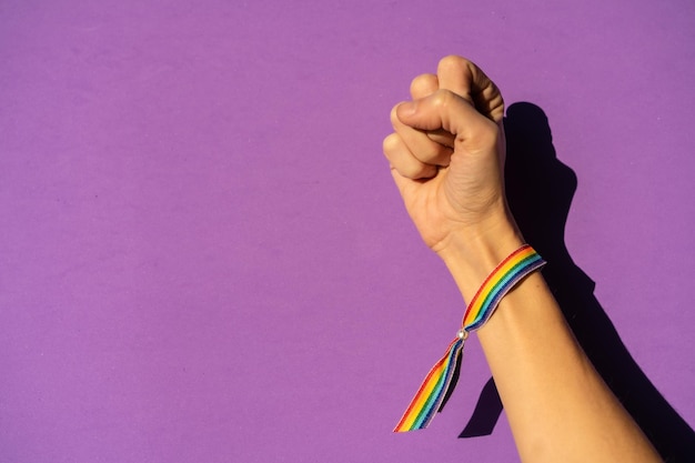 Main d'une femme avec le poing fermé dans le symbole du féminisme en faveur du féminisme fond violet se battant en faveur des femmes force féminine drapeau LGTB