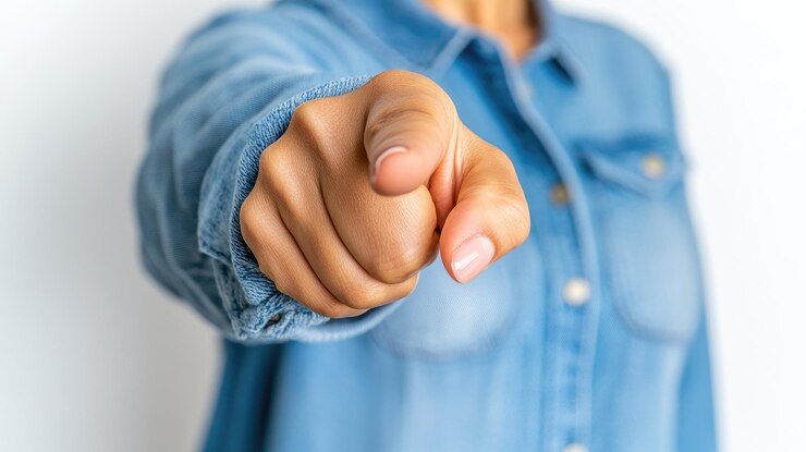 Photo la main d'une femme pointe avec confiance vers la caméra soulignant la connexion et l'intention dans un environnement de studio minimaliste