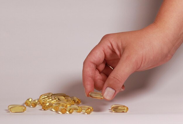 main de femme prenant une capsule d'huile de poisson Omega 3