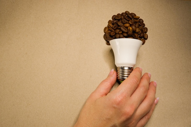 La main de la femme prend une ampoule de grains de café sur du papier artisanal