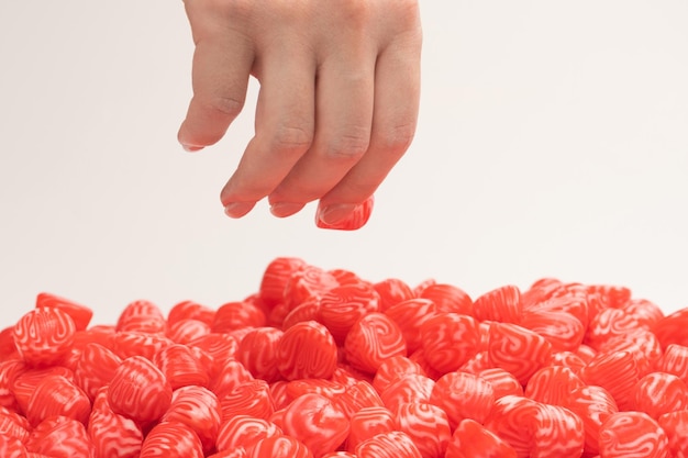 Main de femme prend un bonbon à la gelée sur fond blanc