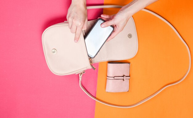 La main de la femme prend le smartphone du sac en cuir