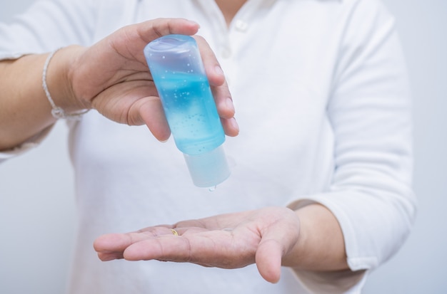 Photo la main de la femme pressant le gel d'alcool du flacon de la pompe pour se nettoyer les mains et prévenir l'infection par le coronavirus, les premiers soins personnels pendant une crise épidémique