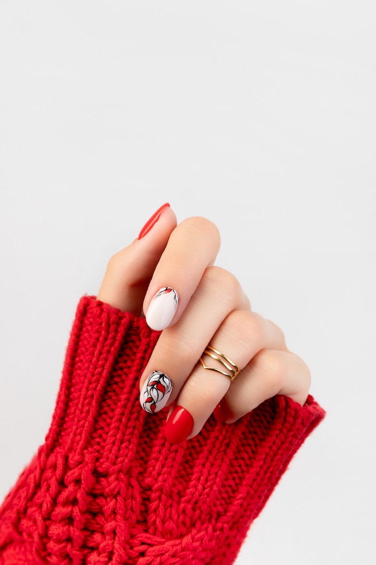 Photo la main de la femme en pull avec manucure rouge sur gris