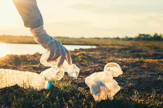 Main de femme ramassant une bouteille en plastique pour le nettoyage au parc