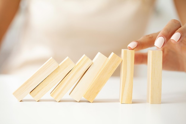 Main de femme s'arrêtant et protégeant le bloc de bois tombant