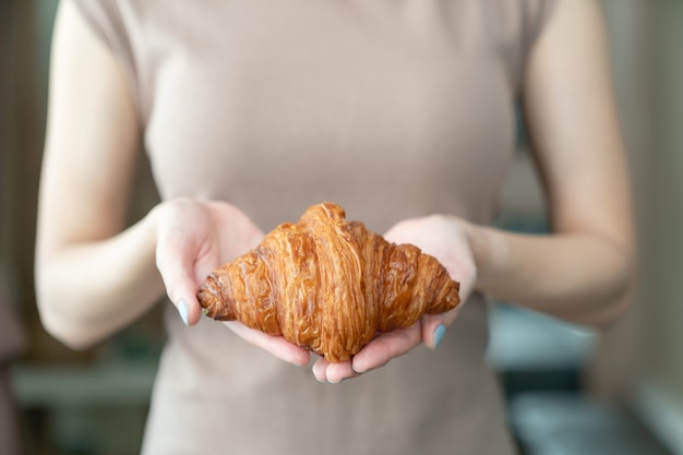 Photo main de femme servant des croissants croustillants au four.