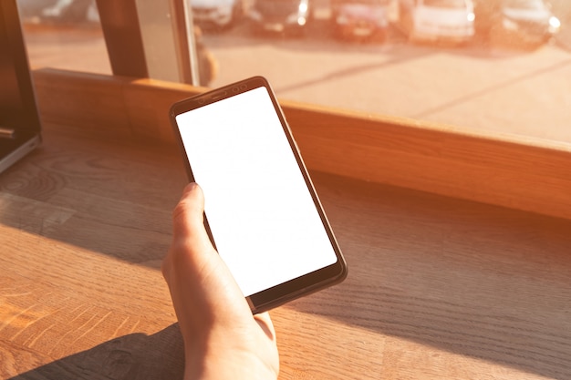 Photo main de femme sur smartphone avec écran blanc.