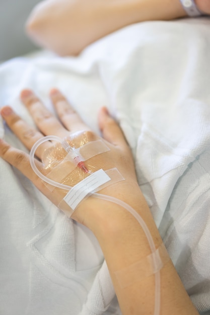 Main de femme avec une solution saline intraveineuse IV sur place à l'hôpital fond blanc