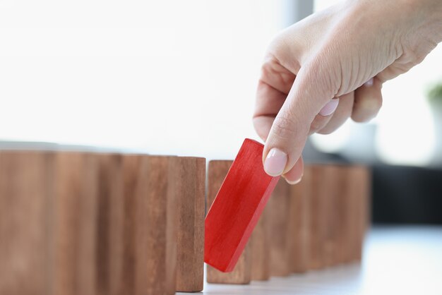 La main de la femme sort un rectangle en bois rouge. Approche individuelle pour résoudre le concept de problèmes commerciaux