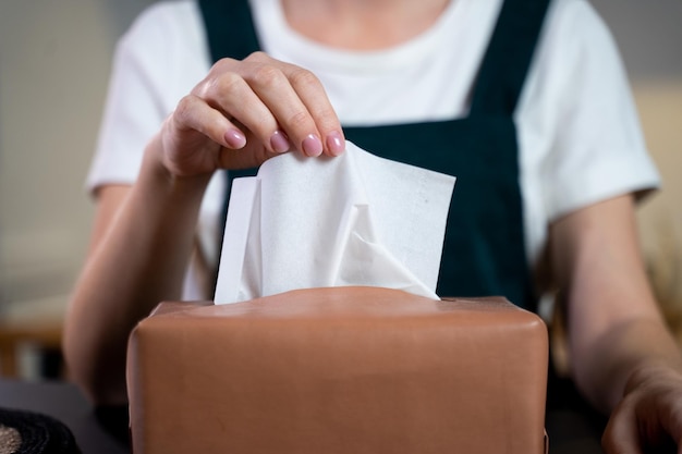 Une main de femme soulevant du papier de soie d'une boîte à serviettes sur la table à manger