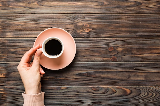 La main d'une femme de style minimaliste tenant une tasse de café sur un fond coloré Coupe d'espresso à vue supérieure plate Place vide pour l'espace de copie de texte Addiction au café À vue supérieure plate