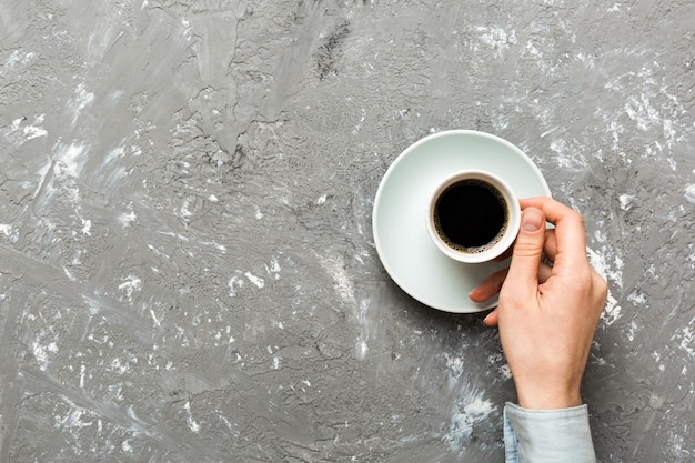 Main de femme de style minimaliste tenant une tasse de café sur fond coloré Tasse à expresso vue de dessus à plat Place vide pour l'espace de copie de texte Dépendance au café Vue de dessus à plat