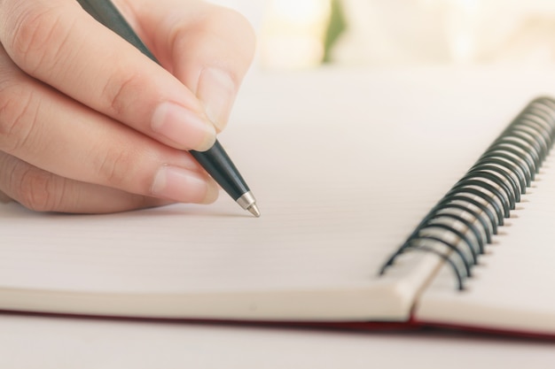 Main de femme avec un stylo écrit sur un cahier